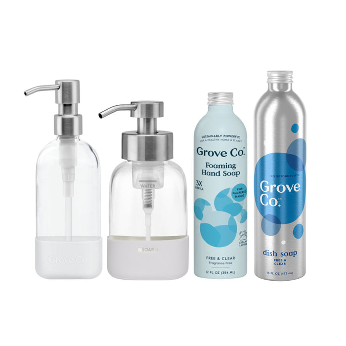 The Foaming Hand & Dish Soap Starter Set by Grove Co. includes two glass pump bottles for soap and two metal bottles labeled Foaming Hand Soap and Dish Soap, with light blue and silver designs, helping reduce plastic waste through their sustainable packaging.