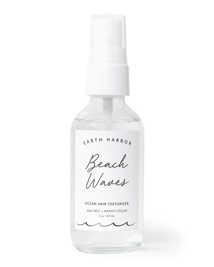 A clear spray bottle labeled Earth Harbor Beach Waves Ocean Hair Texturizer Sea Salt + Mango Cream, 2 oz / 60 mL with a minimalist white label and wavy line design at the bottom.