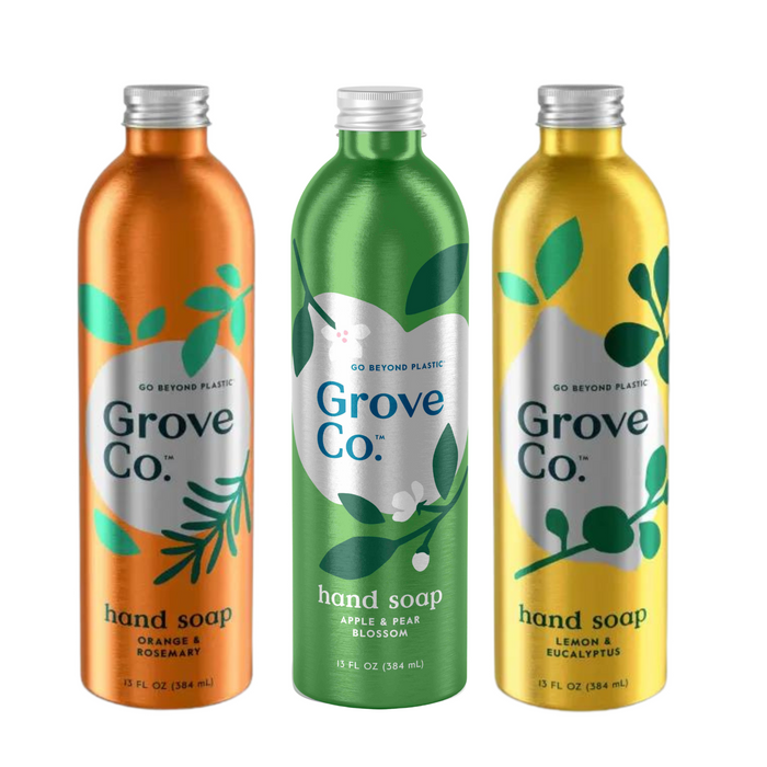 The Grove Collaborative Refillable Fruit Hydrating Hand Soap Set includes three metallic containers in vibrant scents: Orange & Rosemary (orange), Apple & Pear Blossom (green), and Lemon & Eucalyptus (yellow), each adorned with leaf designs and the phrase Go Beyond Plastic.