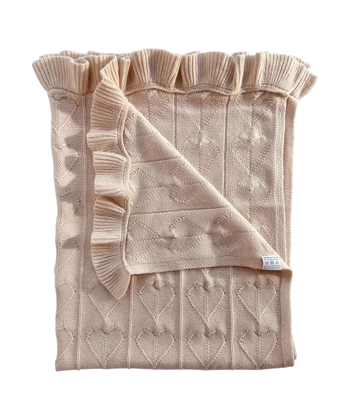 Little Love Baby Blanket - Butter Cream: a light beige organic merino wool baby blanket with a ruffled edge and an all-over heart pattern.