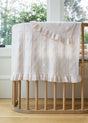 Pale pink AU Baby Little Love Blanket - Cloud in a knit heart pattern with ruffled edges draped over a wooden crib.