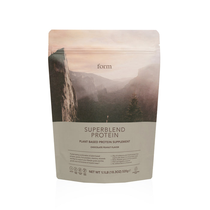 A pouch of Form Superblend Protein, a plant-based protein supplement in chocolate peanut flavor, featuring a scenic mountain landscape on the packaging. The pouch contains 520g (1.1 lb) of product.