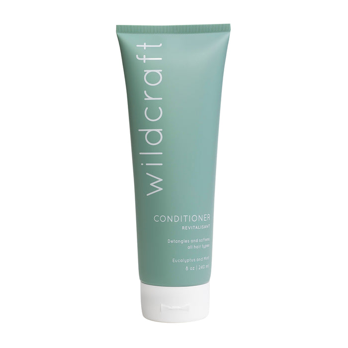 A green squeezable tube of Wildcraft conditioner with white text, labeled Conditioner Revitalisant for all hair types, featuring eucalyptus and mint, 8 oz (240 ml), standing upright on a white background.