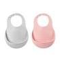 Two silicone baby bibs, one light gray and one light pink, each with an adjustable neck strap and a wide pocket at the bottom for catching food. The bibs are displayed side by side on a white background.