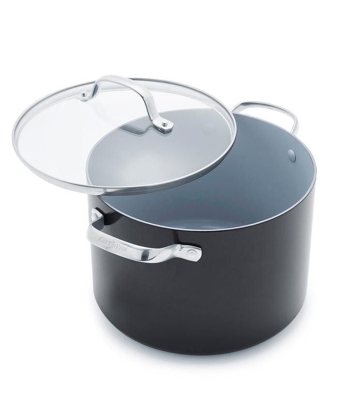 A large, round, black cooking pot with metal handles and a clear glass lid that is slightly tilted open. The interior of the pot appears nonstick and light gray.