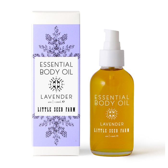 A bottle of Little Seed Farm Body Oils with a pump sits beside its white and lavender box, adorned with botanical illustrations and product details.