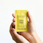 A hand holds a small yellow packet labeled “Deodorant Cream Sample - Grapefruit Lemon” by Little Seed Farm, featuring black text and the brand's circular logo on the front.