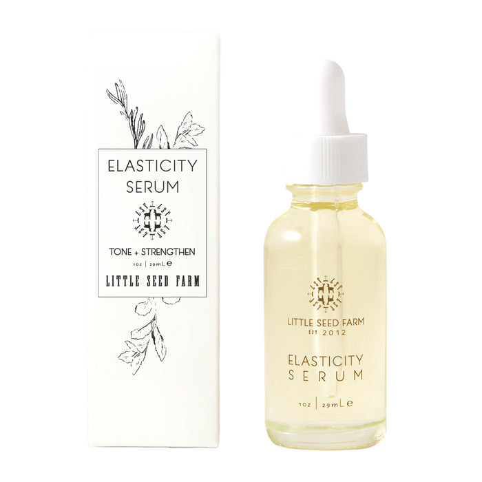 A clear dropper bottle labeled "Elasticity Serum" by Little Seed Farm sits beside its white box, which displays botanical artwork and details the serum’s organic botanicals for supporting skin elasticity.