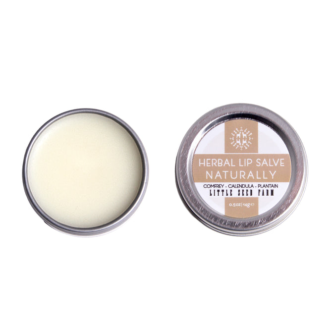 Two small round tins of Little Seed Farm Lip Salve; one open to reveal a smooth, pale balm, the other closed with a label. Made with healing botanicals and organic butters.