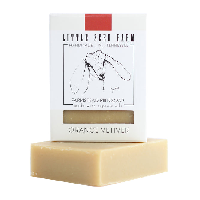 Little Seed Farm’s Orange Vetiver Bar is stacked under white packaging with a goat illustration. Handmade in Tennessee with organic essential oils, it’s ideal for healing dry skin.