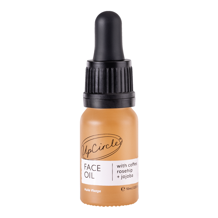 A small amber bottle of UpCircle Face Oil with a black dropper cap. The label reads “with coffee, rosehip + jojoba” and the bottle contains 10ml of product.
