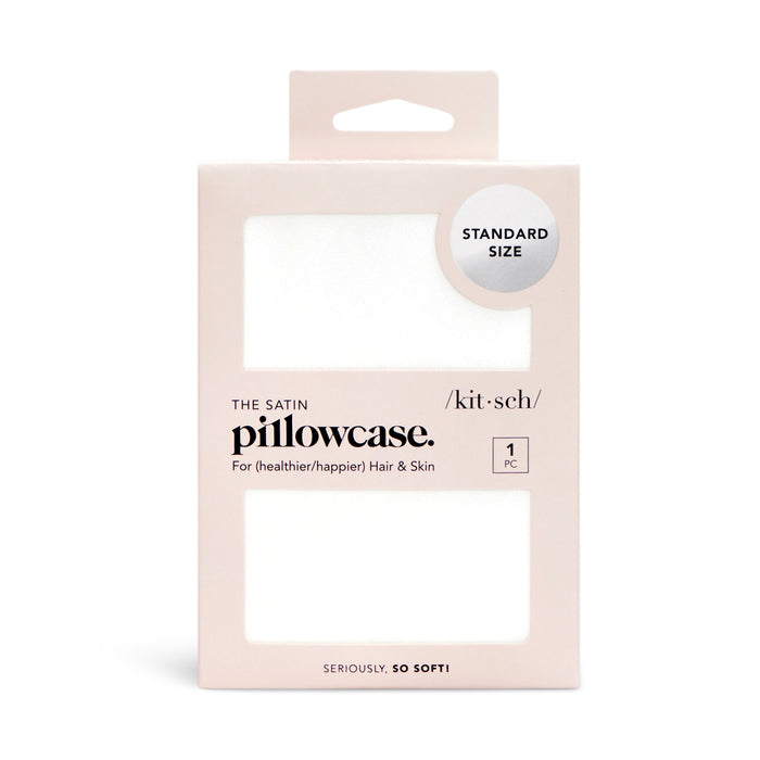 A rectangular, light pink box of Kitsch satin pillowcase, labeled Standard Size and 1 PC. The packaging has a clear window showing the white pillowcase inside. Text highlights benefits for hair and skin.