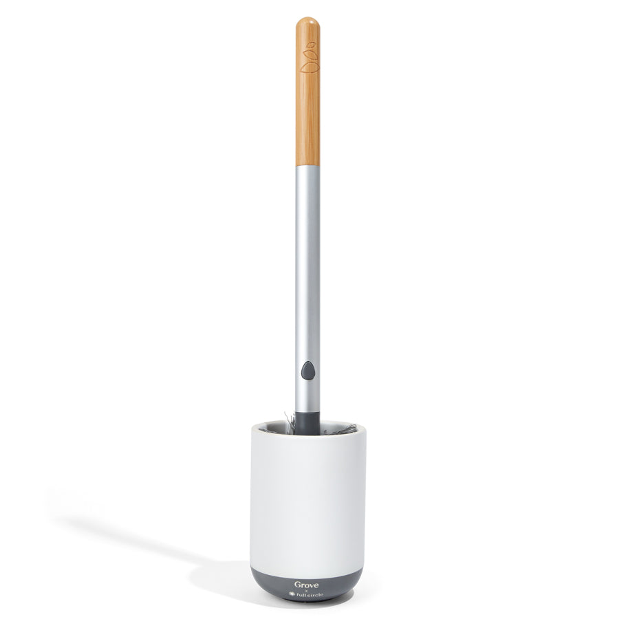 The Grove Co. Toilet Brush with Replaceable Head boasts a gray, wood-textured handle and stands upright in a white holder on a pristine white background.