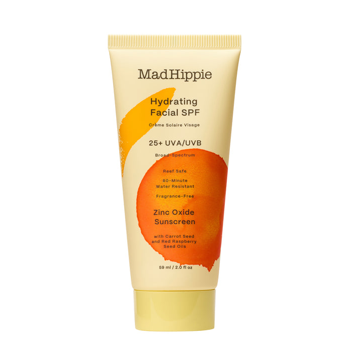 A tube of Mad Hippie Hydrating Facial SPF 25+ UVA/UVB broad spectrum sunscreen with orange and yellow design, labeled as reef safe, water-resistant, fragrance-free, and containing zinc oxide and carrot seed oils.
