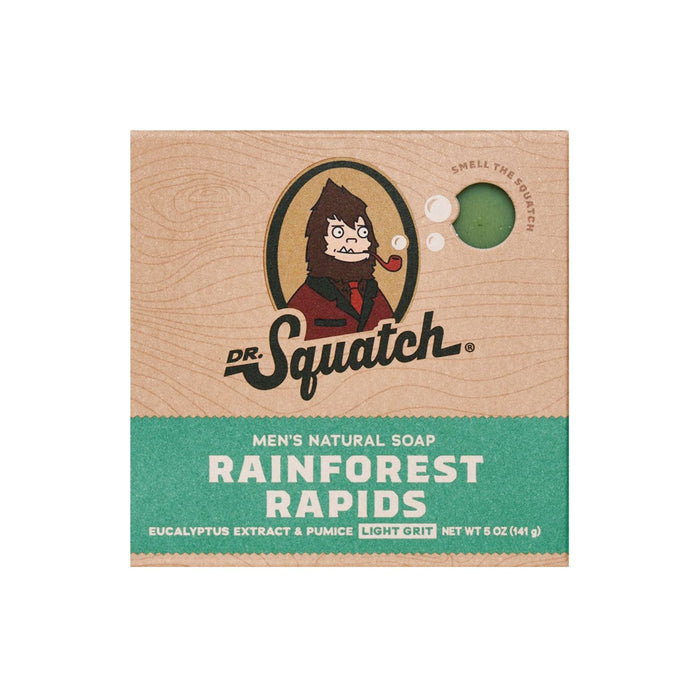 Square package of Dr. Squatch men’s natural soap in “Rainforest Rapids” scent, featuring an illustrated Sasquatch, and labeled with eucalyptus extract, pumice, and “light grit.” A small circular cutout reveals the soap inside.