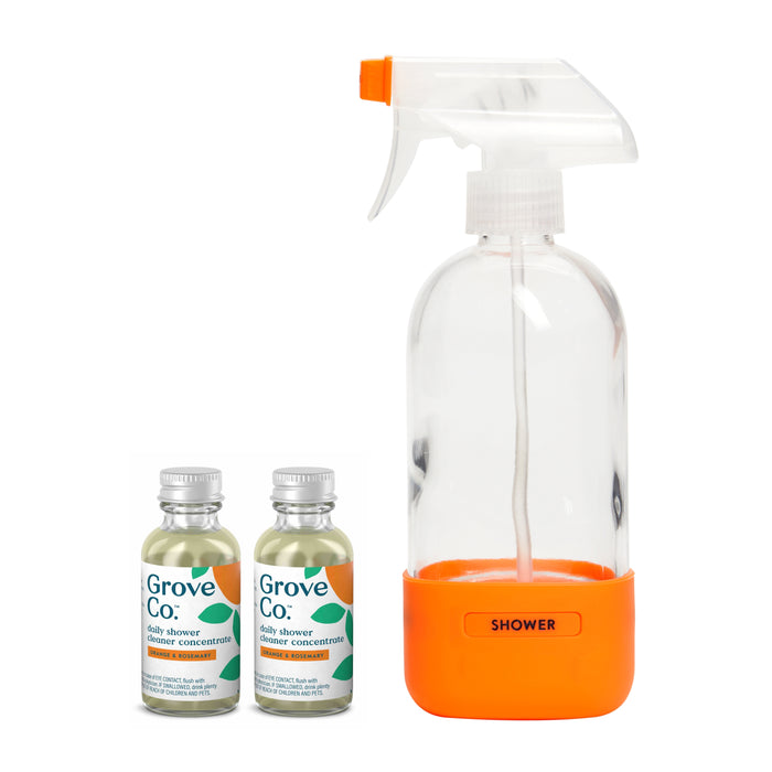 A Grove Co. Daily Shower Cleaner Starter Set includes a clear spray bottle with an orange base labeled Shower and two small bottles of plant-based concentrate featuring silver caps and green labels, offering an easy and eco-friendly way to keep your bathroom fresh.