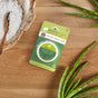 A package of Enviroscent plug hub+ warmer refill sits on a wooden surface, surrounded by a green aloe vera plant and a bowl filled with white bath salts and a wooden spoon.
