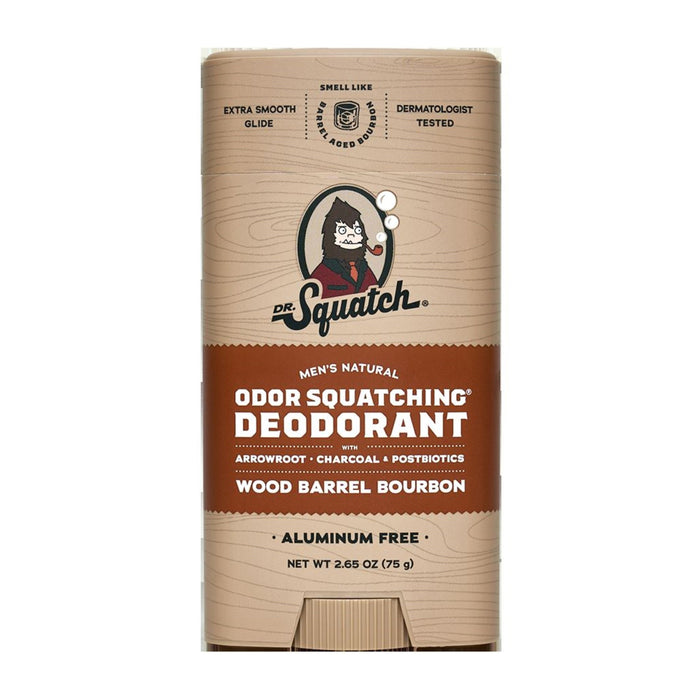 A tan stick of Dr. Squatch Men’s Natural Deodorant in Wood Barrel Bourbon scent, featuring a cartoon man with dark hair and beard, and labeled as aluminum-free with arrowroot, charcoal, and postbiotics.