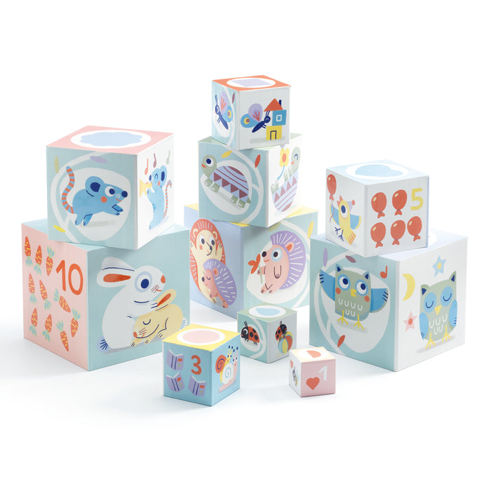 Colorful stacking blocks with animal illustrations and numbers, arranged in a playful pyramid. The blocks feature images of mice, rabbits, owls, birds, numbers, balloons, and other decorative patterns.