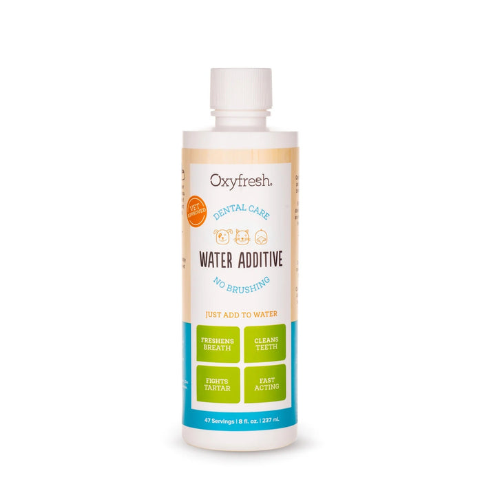 A bottle of Oxyfresh Dental Care Water Additive for pets, featuring icons of a dog and a cat. The label highlights benefits like freshening breath, cleaning teeth, fighting tartar, and fast acting.