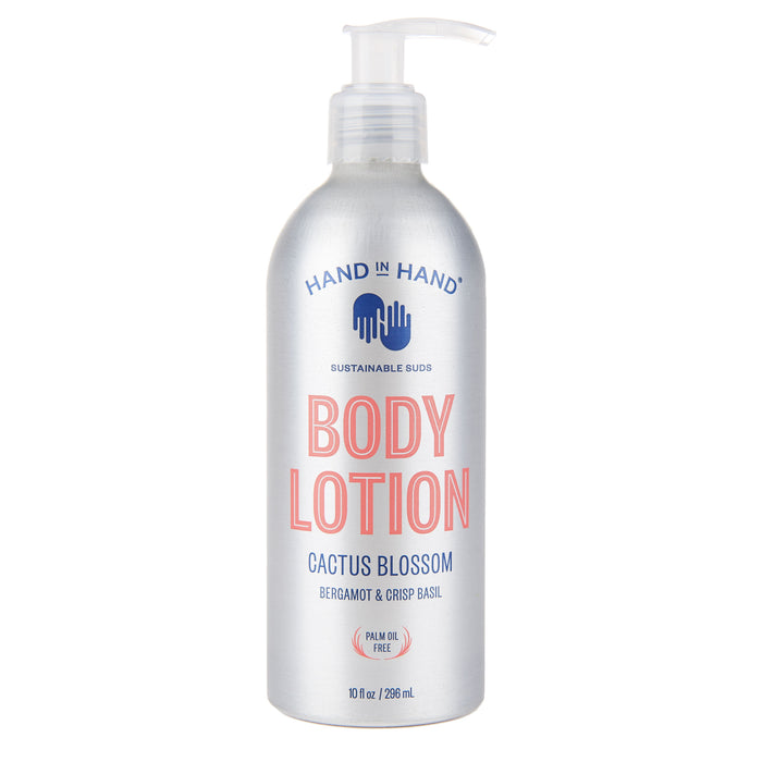 A silver pump bottle of Hand in Hand Body Lotion, labeled “Cactus Blossom” with bergamot and crisp basil, featuring blue and pink text and a palm oil free icon. The bottle contains 10 fl oz (296 ml).