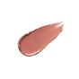 A smooth, teardrop-shaped smear of shimmery rose gold makeup product, likely lipstick or cream blush, on a white background.