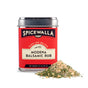 A Spicewalla Mediterranean 3 Pack Collection tin sits beside a small mound of the blend, showcasing mixed herbs and spices inspired by Mediterranean flavors.