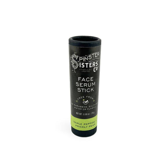 A black cylindrical tube labeled Spinster Sisters Co. Face Serum Stick with text indicating it is triple peptide, prickly pear, free from parabens, sulfates, and plastic, and weighs 0.88 oz (25g).