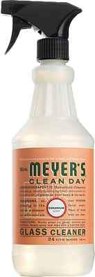 A spray bottle of Mrs. Meyers Glass Cleaner with an ammonia-free formula, black nozzle, and orange label displaying product details and branding.