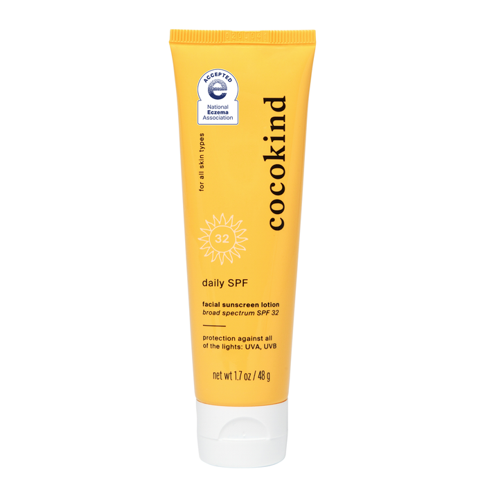 A yellow tube labeled cocokind daily SPF with SPF 32. The text notes its a facial sunscreen lotion with broad spectrum protection for all skin types. The tube is 1.7 oz (48 g) and features a certification badge.