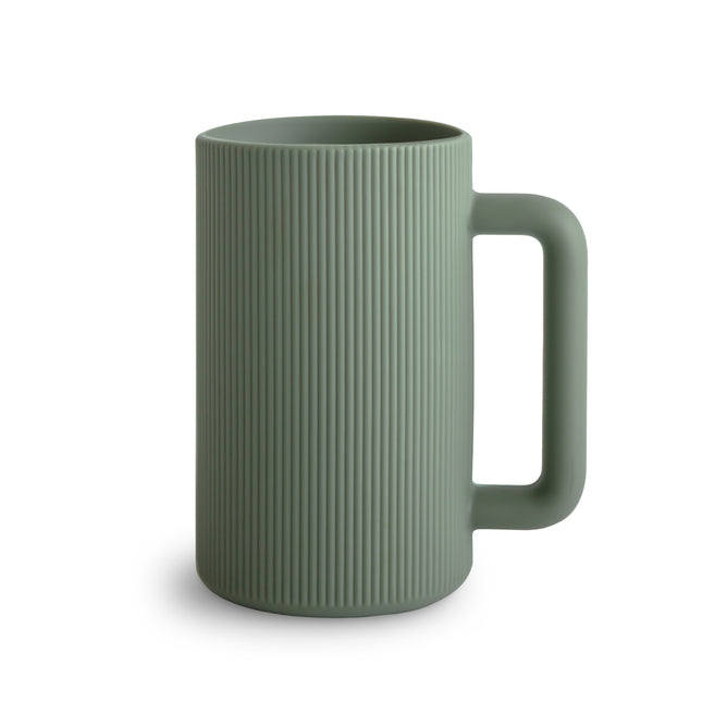 A matte green mushie Bath Rinse Cup made from food-grade silicone, featuring vertical ridges, a cylindrical shape, and an easy-grip handle, shown on a plain white background.
