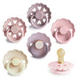 Six mushie FRIGG Natural Rubber Pacifiers (BPA-Free 6-Pack) in pastel pink, purple, and beige feature scalloped-edge shields with heart cutouts and a Click-lock® system; one pacifier is shown from the side.