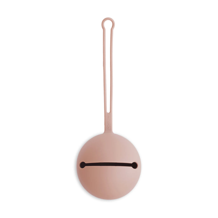 The mushie Silicone Pacifier Holder Case is a round, light pink food-grade silicone case with a long loop handle and horizontal slit opening, perfect for holding and carrying small baby essentials.