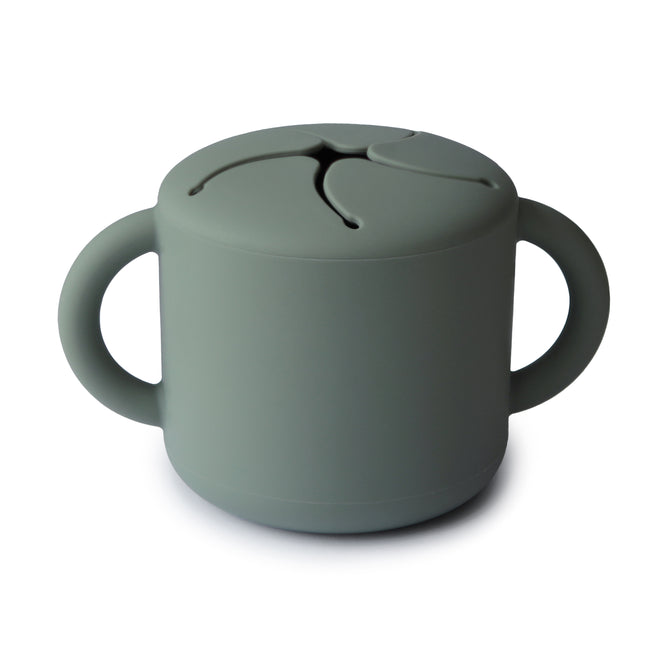 The mushie Silicone Snack Cup – Easy-Grip Handles, BPA-Free is a gray-green food-grade silicone cup with two handles and a flexible, slotted lid for easy snack access and spill prevention—perfect among baby essentials.