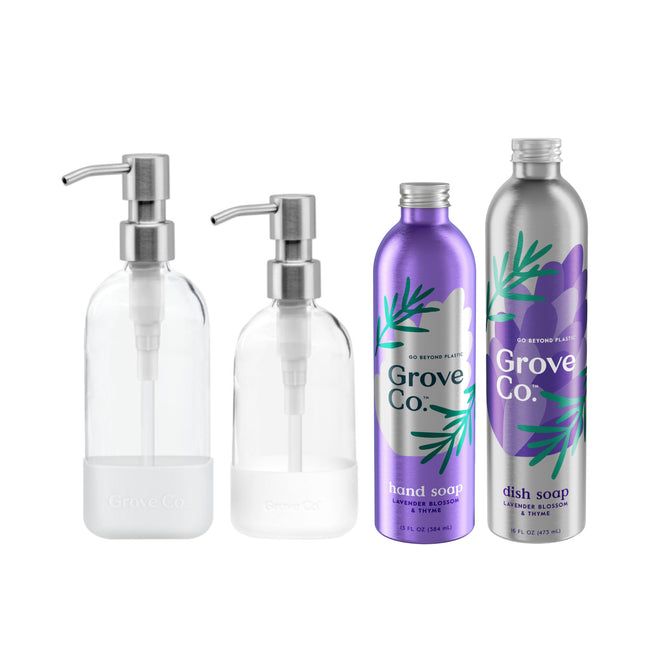 The Hand & Dish Soap Starter Set by Grove Co. includes four bottles: two transparent pump dispensers and two metallic refill bottles, labeled Dish Soap Refill and Hydrating Hand Soap, featuring purple and green botanical designs capturing the essence of Grove soaps.