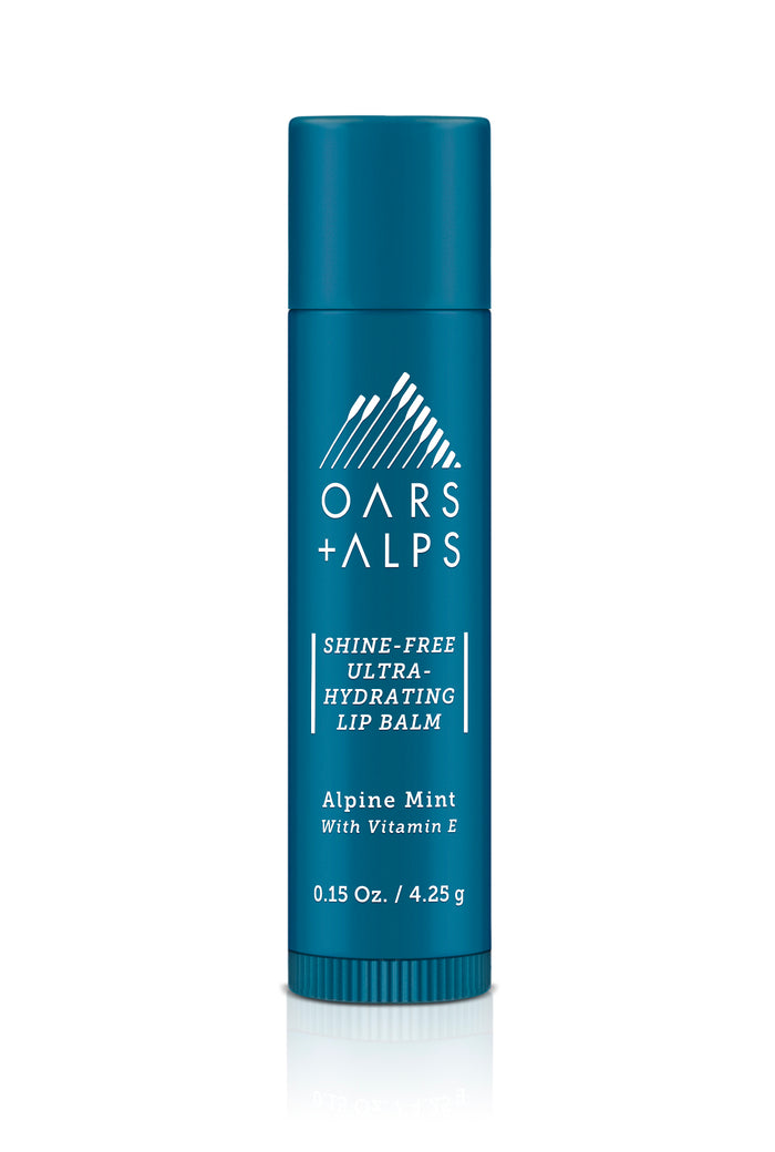 A teal tube of Oars + Alps Shine-Free Ultra-Hydrating Lip Balm in Alpine Mint flavor with Vitamin E, featuring white text and a mountain logo on the front.