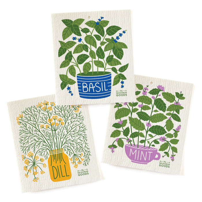 Three illustrated dishcloths featuring potted herbs: basil in a blue pot, dill in a yellow jar, and mint in a purple cup. Each has the herbs name written on the pot and green leafy stems.