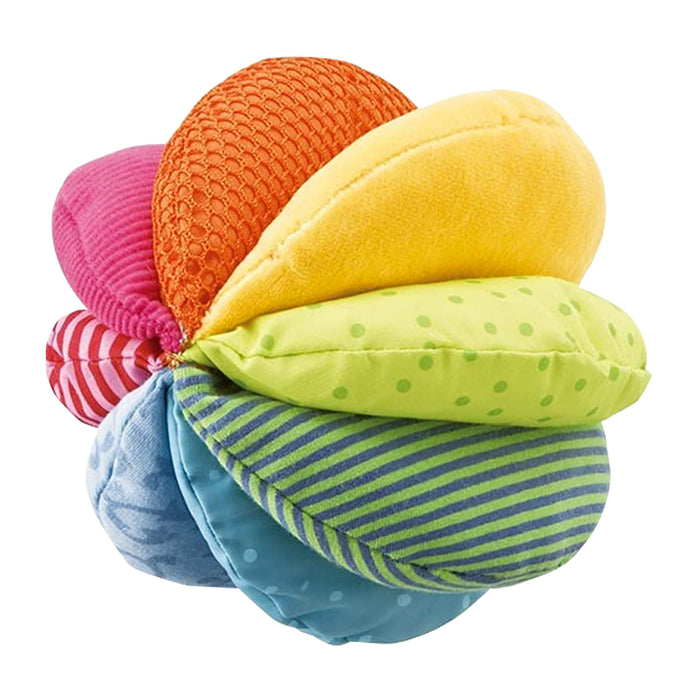 A colorful plush ball made of eight textured fabric segments in red, orange, yellow, green, and blue, featuring various patterns like stripes, dots, and mesh, arranged in a circular shape.