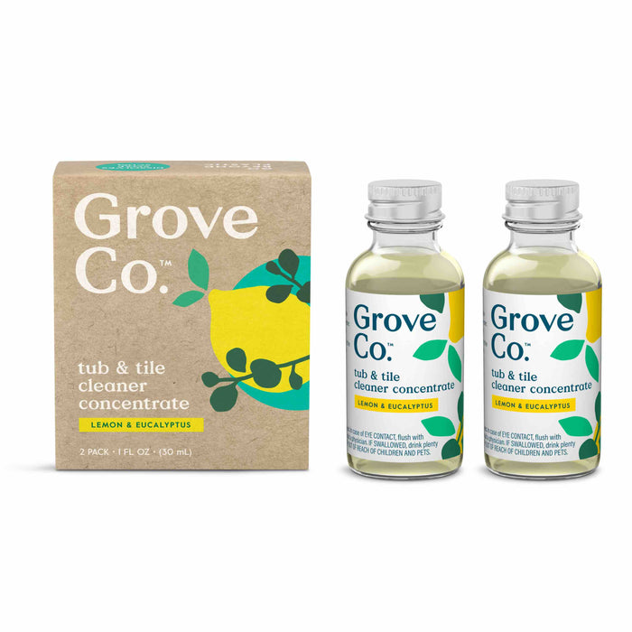 Two small bottles of Grove Co. tub & tile cleaner concentrate (lemon & eucalyptus) sit next to their cardboard packaging, which features a yellow lemon and green leaves graphic.