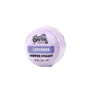 The Spinster Sisters Co. Lavender Shower Steamer is a round, lavender-colored product offering aromatherapeutic scents. Infused with essential oils, it weighs 1.5 oz (42 g) and is elegantly showcased against a white background.