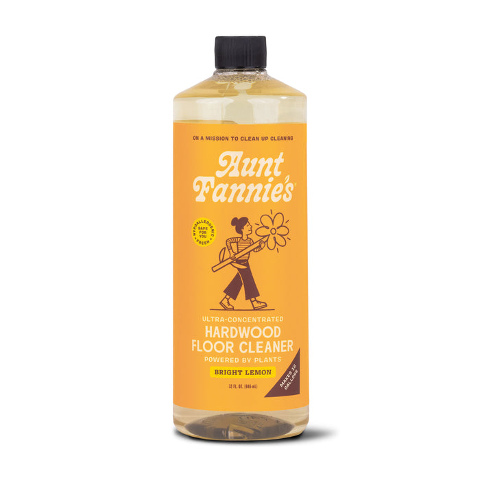 A bottle of Aunt Fannies Hardwood Floor Cleaner in Bright Lemon scent. The label is orange with white and yellow text and features an illustration of a woman carrying a flower.