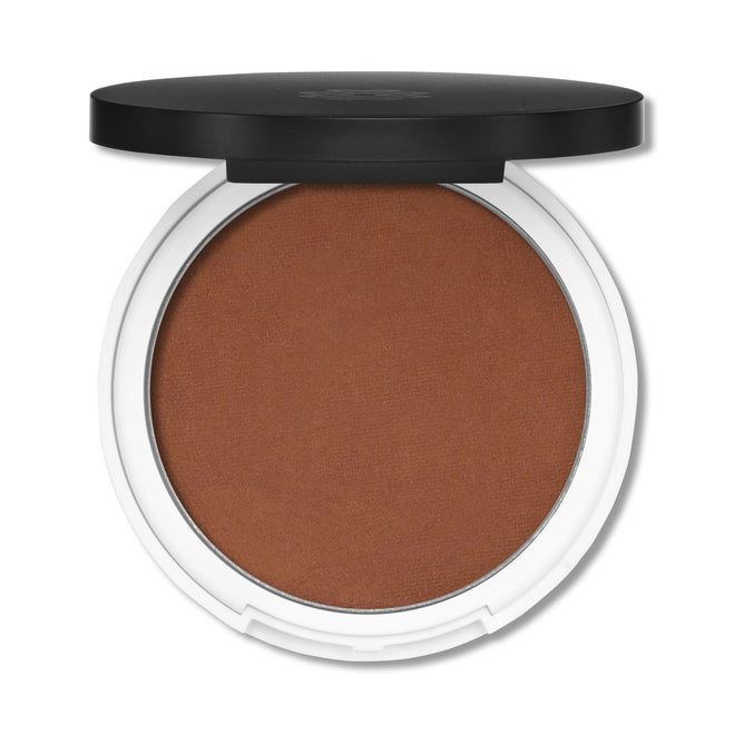 A round, open compact from Lily Lolo contains a deep brown Pressed Bronzer. It features a black lid and white base encasing natural minerals. The image promises a sun-kissed glow with each application.