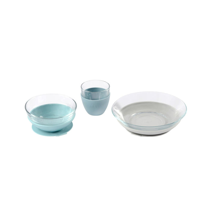Three clear glass dishes with pale blue silicone bases: a small bowl, a cup, and a shallow plate, all placed on a white background.