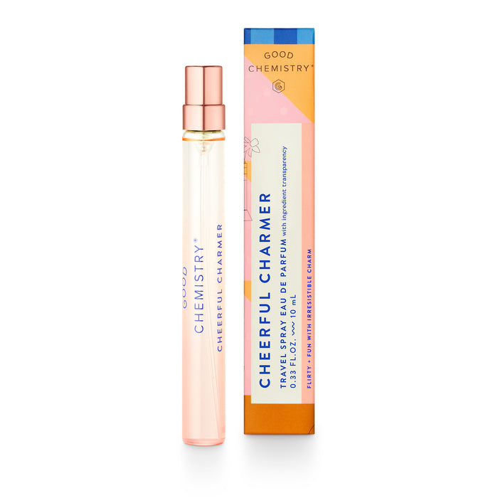 A clear glass perfume spray bottle labeled Good Chemistry Cheerful Charmer stands beside a colorful rectangular box with the same branding and orange, pink, and blue accents.