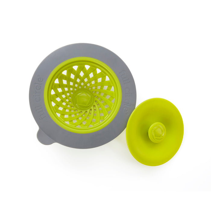 A gray and green silicone sink strainer and stopper set. The strainer has a circular design with slits for water flow, while the stopper is solid with a small handle in the center.