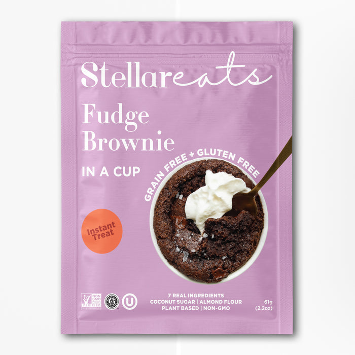 A pink packet of Stellareats Fudge Brownie in a Cup, featuring a photo of a brownie topped with whipped cream and a spoon. The packaging highlights that its grain-free, gluten-free, and made with real ingredients.