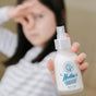 A child holds out a bottle of Nellies Toilet Spray - Lemongrass with one hand while pinching their nose with the other, highlighting its fresh lemongrass scent and green cleaning qualities.