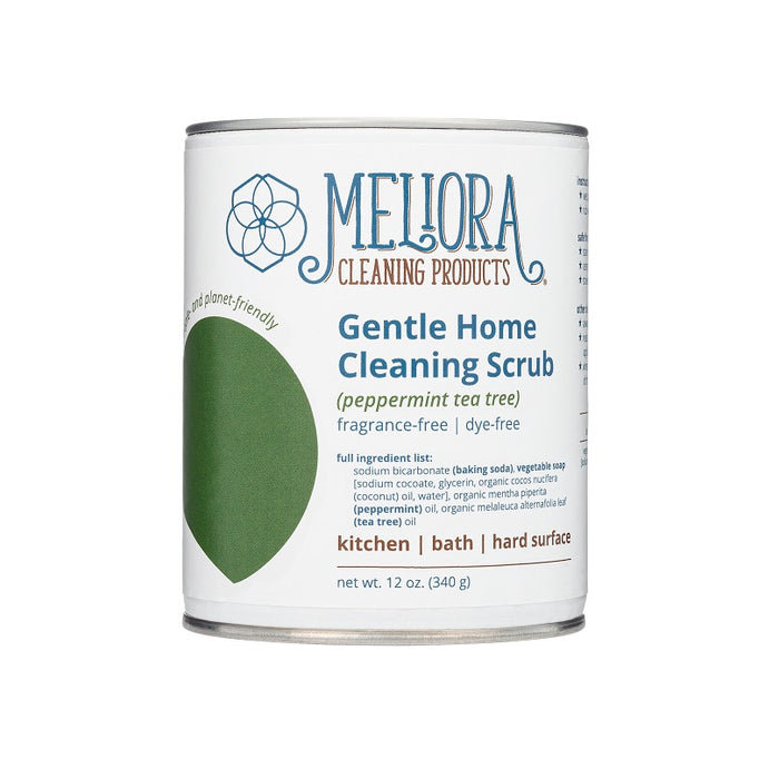 A cylindrical can of Meliora Gentle Home Cleaning Scrub (peppermint tea tree). The label highlights that it is fragrance-free, dye-free, and planet-friendly. The can contains 12 oz (340 g) and lists suitable uses: kitchen, bath, and hard surfaces.