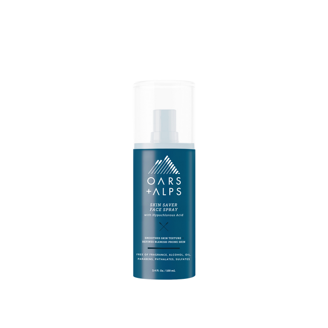 A blue bottle of Oars + Alps Skin Saver Face Spray with a white cap is shown on a plain white background. The label features key benefits in white text, including hypochlorous acid to soothe irritated skin.
