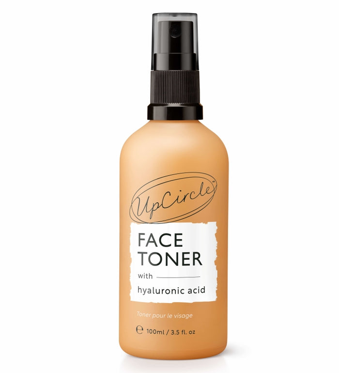 A bottle of UpCircle Face Toner with hyaluronic acid, featuring a black spray cap and an amber-colored container. The label displays the product name and size, 100ml (3.5 fl. oz), in black and white text.